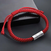 925 Sterling Silver Letter Blessing String Bracelet – Red knotted cord with silver engraved metal bar charm on dark gray surface with lifestyle props