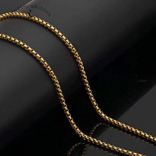 Zodiac Spin Necklace – gold box chain close up, black reflective background showing metal link detail, Buddhist necklace chain