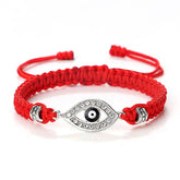 Red cord evil eye bracelet with silver crystal evil eye charm on white background