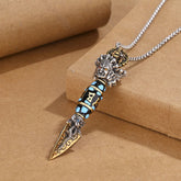 Tibetan Dzi Bead Dorje Pendant - Diagonal view on kraft paper showing deity head and turquoise inlays, dorje vajra necklace