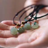 Jade Peace Buckle Lotus Necklace – Four jade pendants with lotus pod and bi-disc on colored cords in palm, jade necklace
