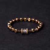 Om Mani Padme Hum Brass Bracelet - Brass hexagonal beads with prayer wheel focal, dark backdrop, men spiritual