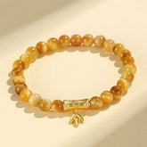 Tiger Eye Fu Bamboo Koi Lotus Bracelet – golden tiger eye beads with gold bamboo and leaf charm on cream, flat lay