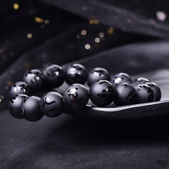 Black Onyx Mantra Bracelet – Spherical black stone beads with engraved symbols on dark surface, spiritual jewelry