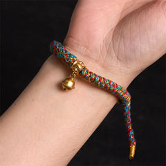 Zakiram Om Mani Padme Hum Charm Bracelet – Worn on wrist showing colorful braid and gold bell, close-up fit view