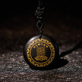 Black Obsidian Multi-Crystal Purification Pendant - low-angle view on dark slate, gold swastika & lotus on glossy obsidian, spiritual