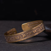 Om Mani Padme Hum Copper Brass Bangle – Three-quarter view on dark stone, mantra bracelet