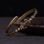 PiXiu Coin Bangle – Two stacked antique brass cuffs with PiXiu coin detail on dark surface