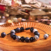 Black Obsidian Lava Rock Yin Yang Bracelet - curved on wooden plate with dried flowers, obsidian lava rock bracelet