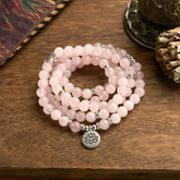 Rose Quartz Lotus Mala Bracelet - pink beads coiled on wood, serene