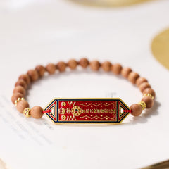 Sandalwood Bead Bagua Yin Yang Bracelet - elevated angle on book pages showing red enamel hexagonal pendant, wooden bead j...