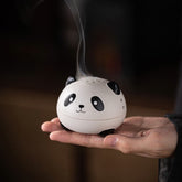 Cute Panda Ceramic Incense Burner – Round panda head held in palm with smoke rising from top vents, calming