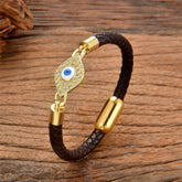 Brown braided leather evil eye bracelet with gold pave crystal charm on rustic wood