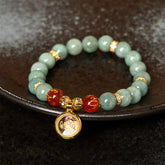 Green Jade Om Bracelet on dark ceramic dish, jade charm bracelet