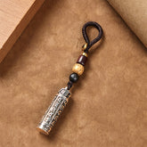 Tibetan Copper Vajra Key Chain – diagonal view on kraft paper with mantra cylinder and bead cord, protection