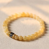 Om Mani Padme Hum Bracelet – Curved topaz beads with gold mantra spacer on cream fabric, spiritual wrist jewelry