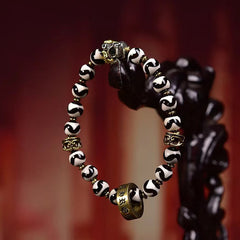 Tibetan Dzi Bead & Copper Om Mani Padme Hum Bracelet - Side view on carved wooden stand displaying beaded circle, dzi bracelet