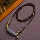 Tibetan Dzi Bead Agate Protection Pendant – full necklace laid flat on textured fabric, agate bead with metalwork, dzi bea...