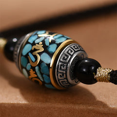 Dzi Bead Om Mani Padme Hum Rotatable Pendant – Macro close-up of silver Greek key end cap and gold mantra engraving, prayer wheel pendant