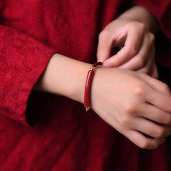 Cinnabar Heart Sutra Blessing Bracelet – worn on wrist showing carved cylinder and braided cord, red cord bracelet