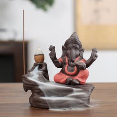 Ganesh Backflow Incense Burner - Four-armed elephant god in charcoal with rust orange, smoke waterfall, Ganesha statue