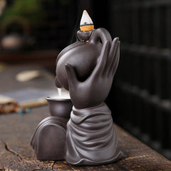 Buddha Hand Teapot Incense Burner – Mudra hand holds vessel, white smoke flows into cup, dark clay art