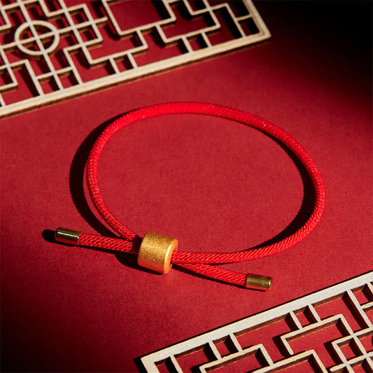 Lucky red string bracelet with gold sliding bead closure, braided crimson cord on red display with traditional Chinese lattice frames