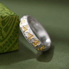 Hammered Om Mani Padme Hum Ring - resting against green prop with gold script, tibetan silver ring