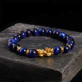 Multi-Color Tiger Eye PiXiu bracelet – blue tiger eye beads with gold charm on dark stone, feng shui wealth