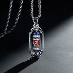 Om Mani Padme Hum Prayer Wheel Pendant – Three-quarter view of prayer wheel with blue and red enamel bands on rope chain, ...