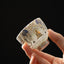 White Thangka Buddha Kung Fu Tea Cup – hand-held side view showing gold Buddha and blue clouds on white ceramic, closeup detail