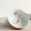 Koi Fish & Lotus Tea Cup – Tilted view of koi and lotus interior on linen fabric, ceramic tea cup
