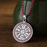Om Mani Padme Hum Pendant Necklace – colorful cord pendant hanging before green ceramic on wood, Buddhist spiritual jewelry