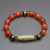 Red Agate Nine-Eye Dzi Bead Bracelet – top-down view on gray, warm carnelian beads with cylindrical dzi focal bead