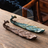 Peacock Shape Ceramic Incense Burner – Two peacock burners in bronze and teal with gold accents, one lit with rising smoke, ceramic incense holder