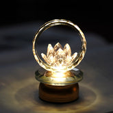 Crystal lotus in faceted ring on illuminated base, warm amber glow, lotus lamp