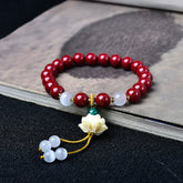 Cinnabar Cat's Eye Lotus Blessing Bracelet - red beads with carved lotus charm on ink-wash book, spiritual jewelry