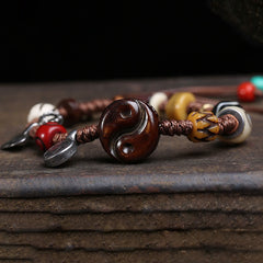 Yin Yang Bone Bracelet - macro of carved wooden yin yang bead on brown braided rope