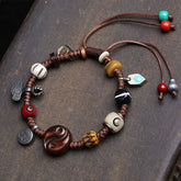 Yin Yang Bone Bracelet - flat lay on dark stone, carved bone beads and ethnic charms, cord