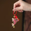 Koi Fish Prosperity Keychain - red koi charm with gold accents and rainbow tassel in hand