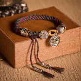 Fu Swastika Rope Bracelet - Multicolor braided cord with silver fortune Fu charm and metal beads on brown display box, handmade bracelet