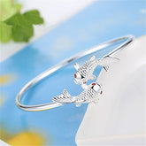 Double Fish Cuff – silver open bracelet with two detailed koi fish and red gemstone eyes