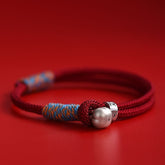 Persimmon Cord Bracelet – Red braided cord with silver persimmon charm on red background, luck bracelet