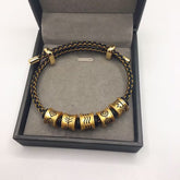 Five Elements Bracelet – black gold braided cord with five engraved gold beads in open black gift box, luxury presentation