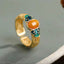 Amber Enamel Ring – gold open band with orange resin stone and blue cloud enamel on gray