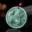 Jade Kirin Pendant – Green nephrite qilin relief carving with ruyi clouds and red carnelian bead on black, prosperity