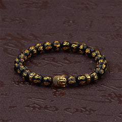 Tibetan Buddha Om Mani Padme Hum Amulet Bracelet - faceted black obsidian beads with gold Tibetan script Om Mani Padme Hum, gold Buddha head amulet, ornate gold spacer beads, wrist mala on dark rustic surface