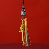 Tibetan Prayer Wheel Keychain – gold-tone prayer wheel pendant with colorful silk tassel, turquoise beads and auspicious knot charm, red background, front vertical view