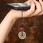 Cinnabar Bagua Mountain Ghost phone charm with red lion head bead and bronze coin, attached to smartphone