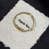 Double-Layer Gourd Bracelet – Gold chain and blue braided rope with gourd charm on white felt, feng shui protection